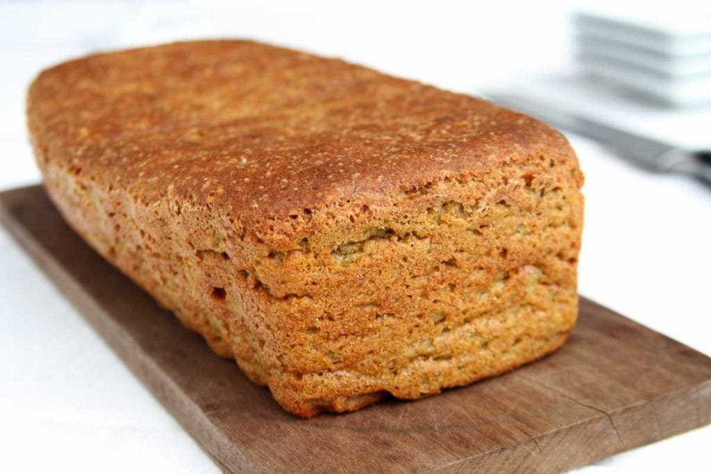 Pão de forma sobre tábua de madeira escura em uma mesa branca