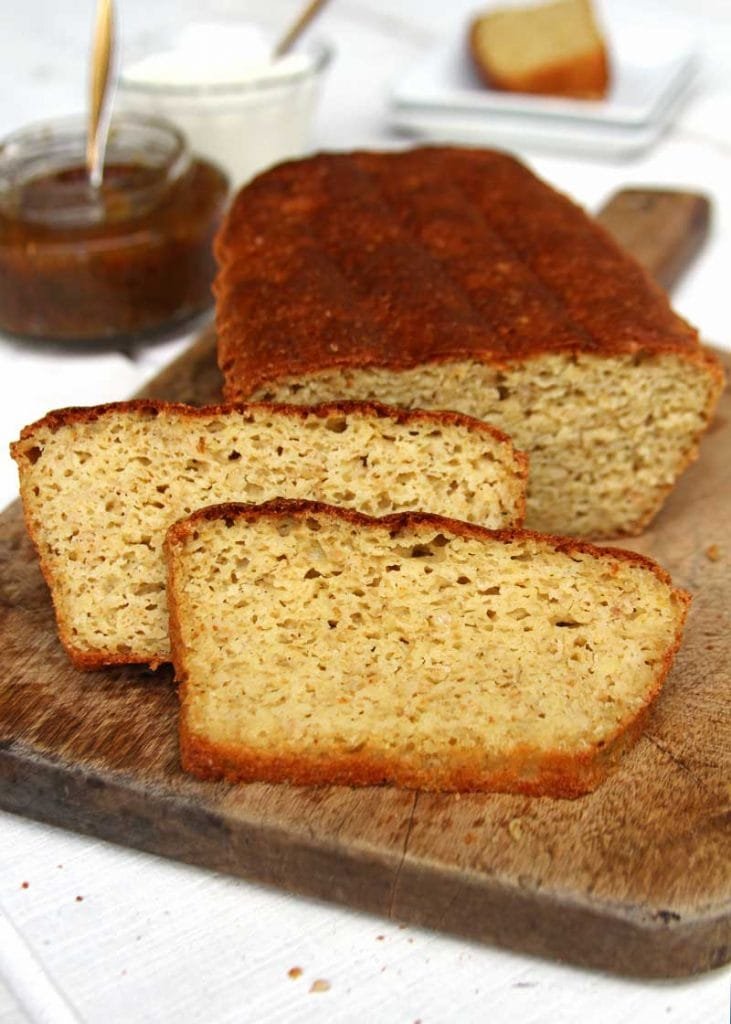 Pão de forma fatiado sobre tábua de madeira em mesa branca