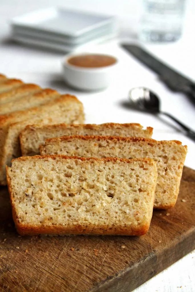 Pão fatiado na tábua de madeira sobre mesa branca