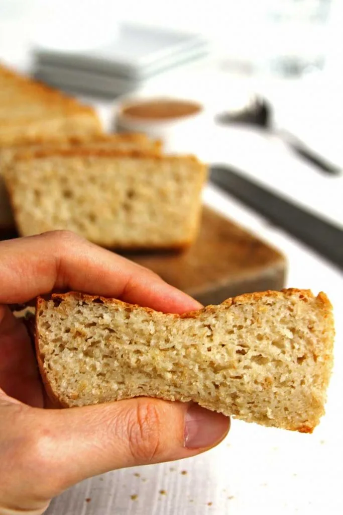 Mão apertando fatia de pão sobre uma mesa branca