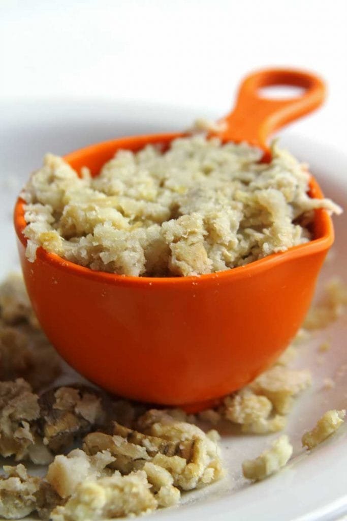 Batata-doce cozida e esmagada dentro de uma xícara laranja sobre um prato branco