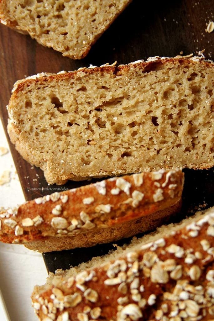 Pão de aveia integral fatiado sobre tábua de madeira marrom