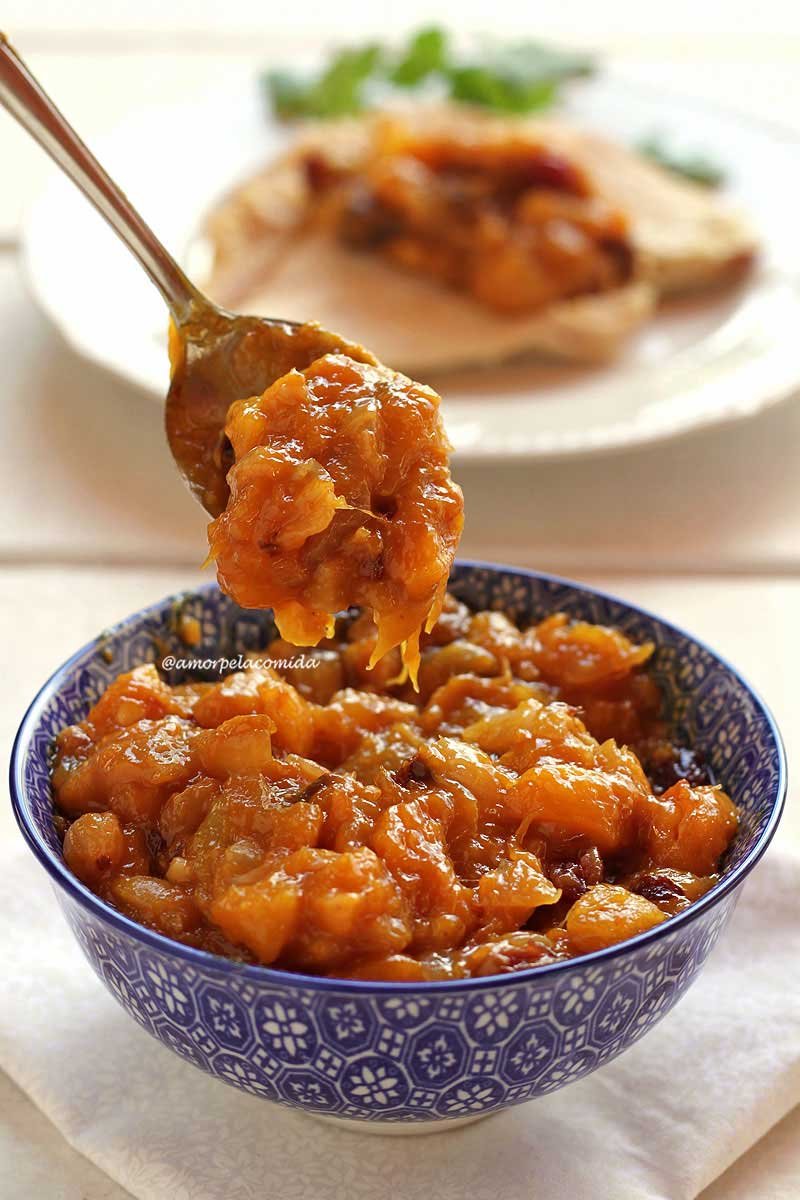 Pote azul com chutney de manga em uma colher de metal