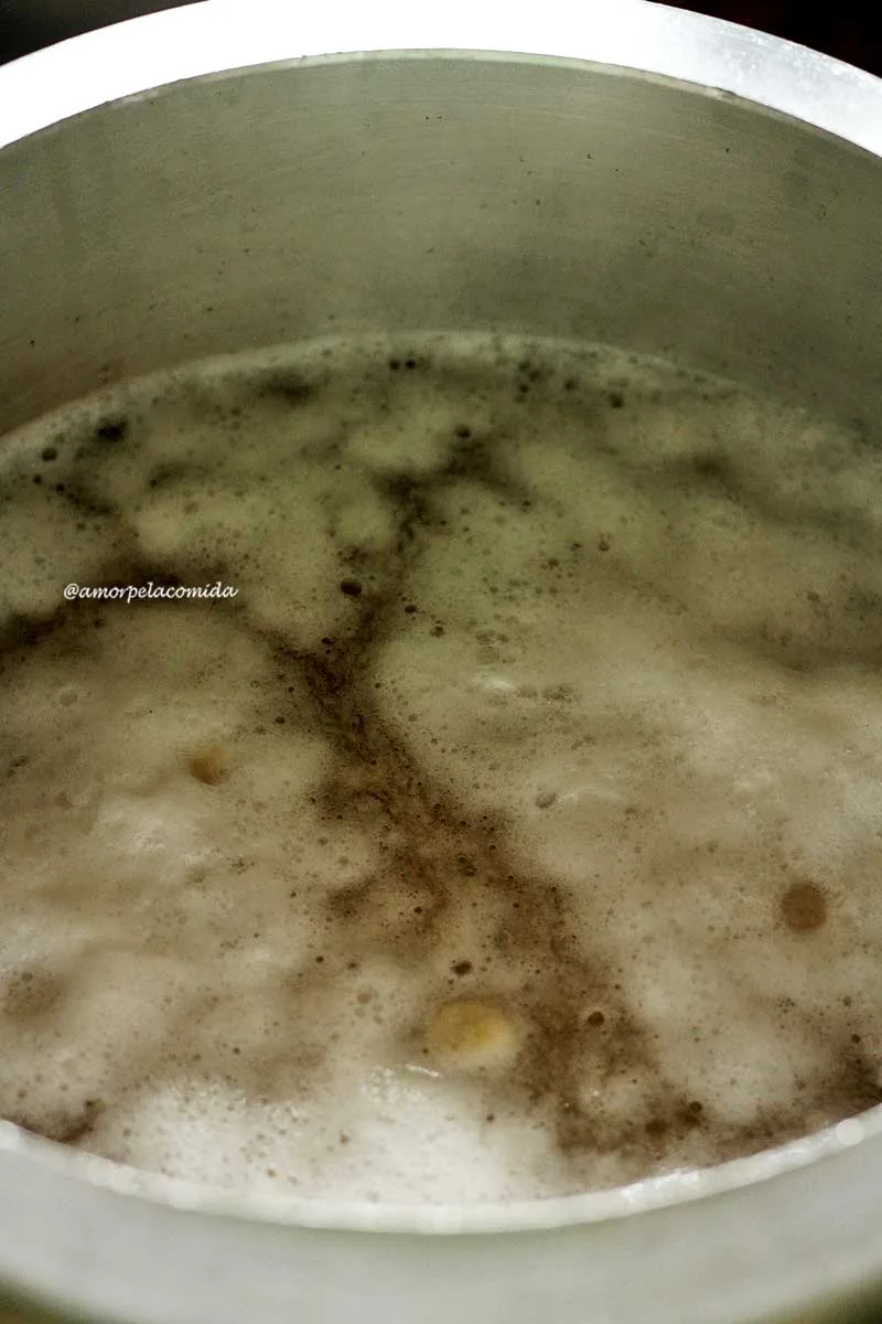 Panela de pressão fervendo grão-de-bico com espuma branca na superfície