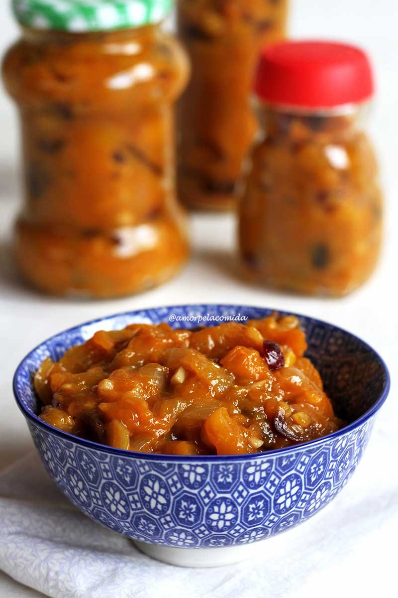 Pote azul com chutney de manga sobre mesa branca com vidro ao fundo