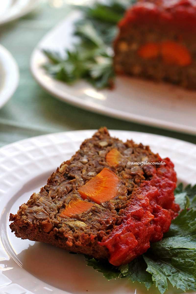 Fatia de bolo de carne recheada com cenoura coberta com molho de tomate sobre prato branco