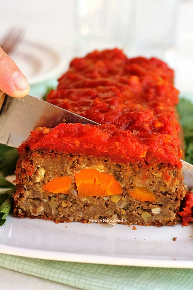 Bolo de carne vegetal recheado com cenoura sendo fatiado