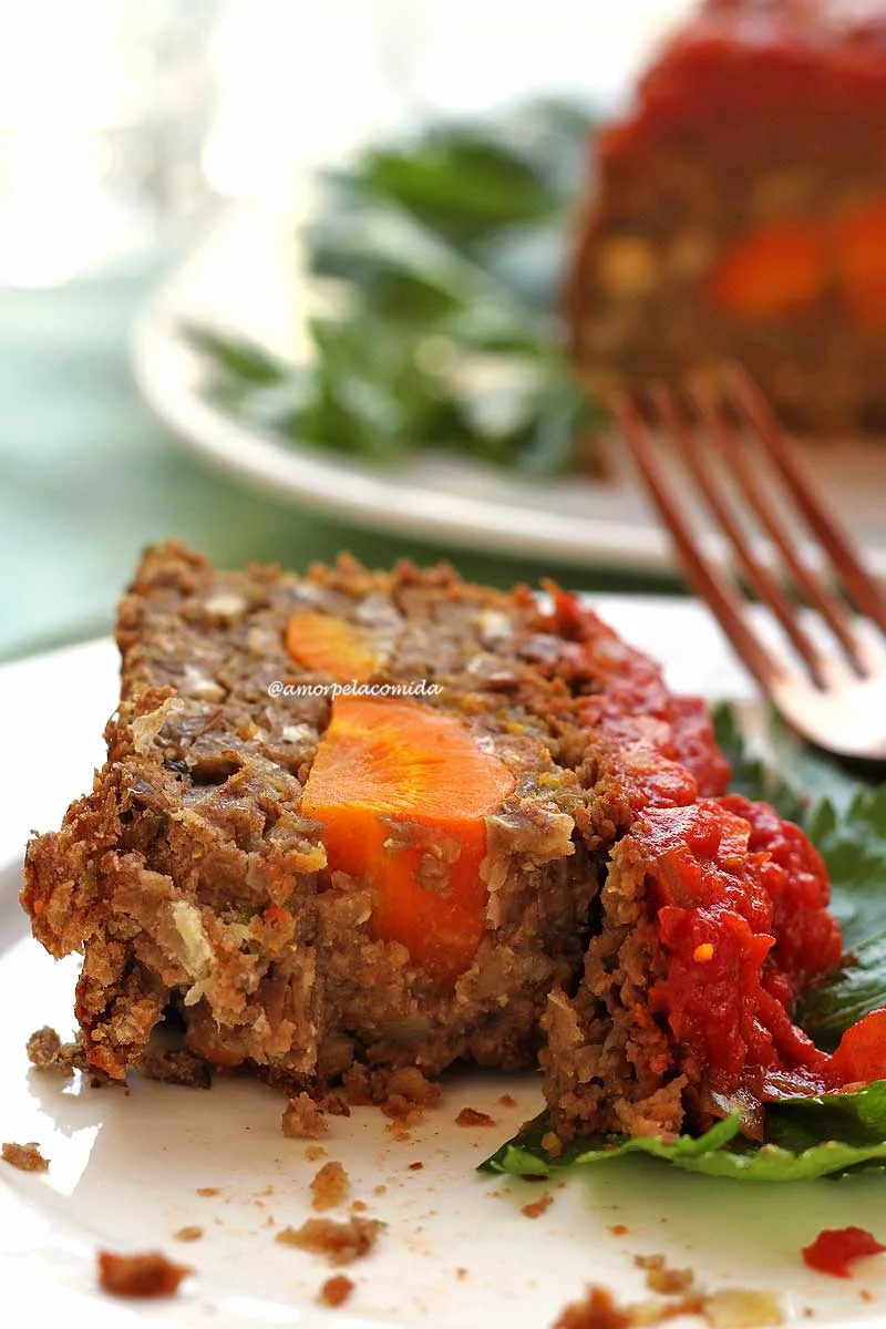 Fatia de bolo de carne vegetal sobre prato branco com garfo