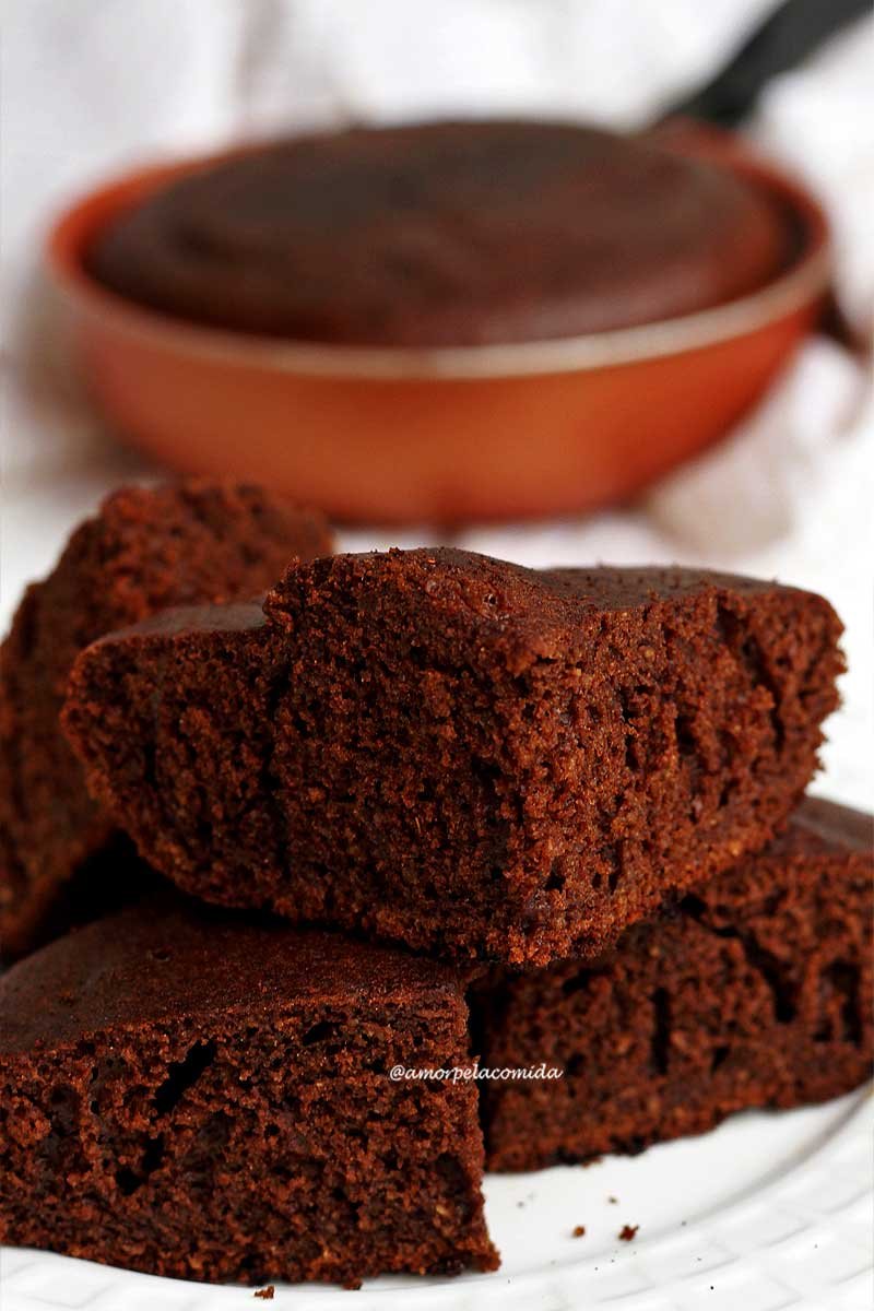 Quatro pedaços de bolo de chocolate empilhados sobre prato branco