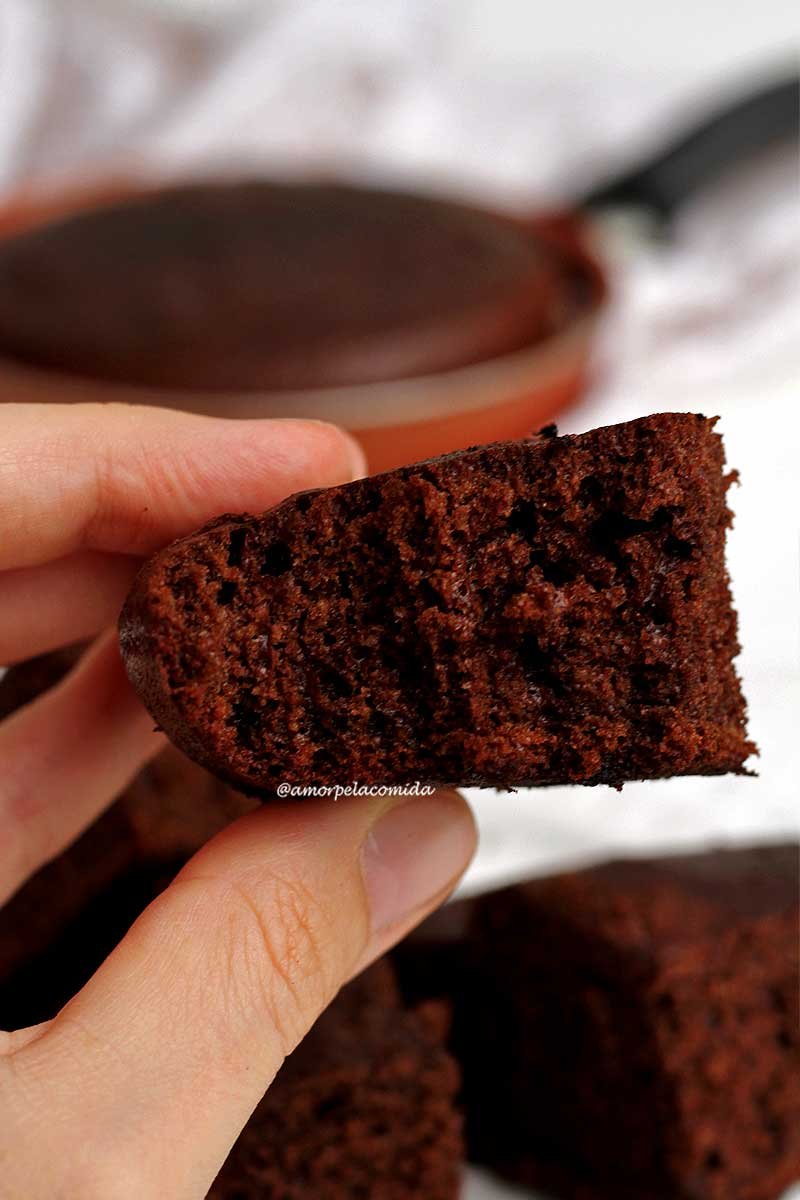 Mão segurando pedaço de bolo de chocolate feito na frigideira