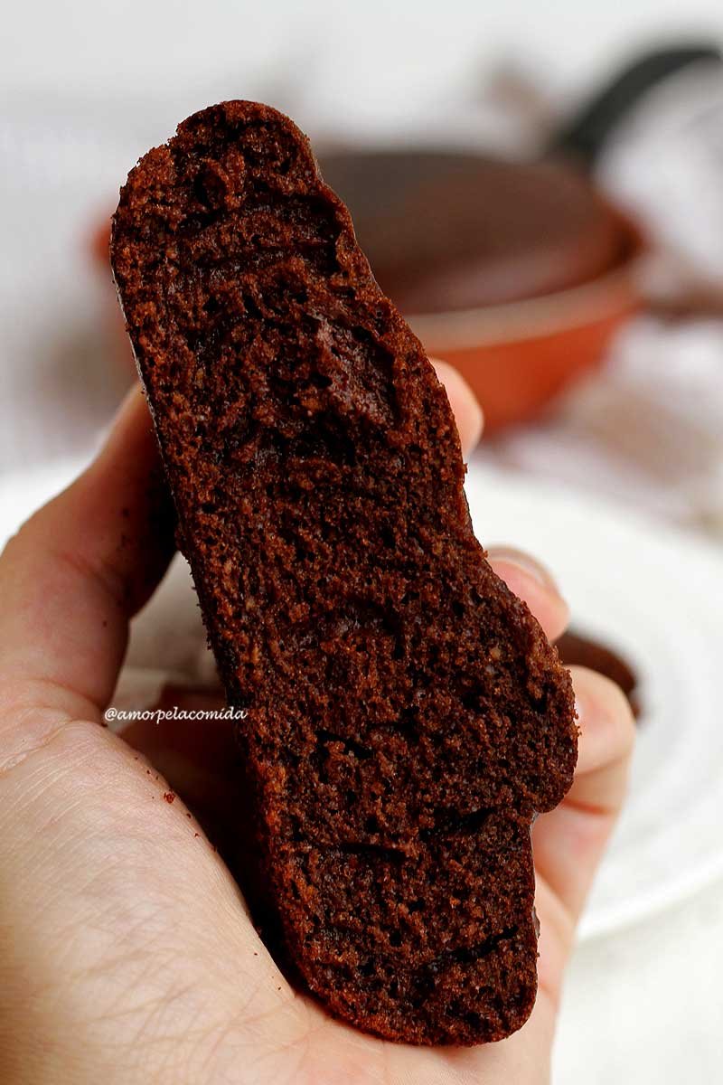 Mão segurando pedaço de bolo de chocolate fofinho feito na frigideira