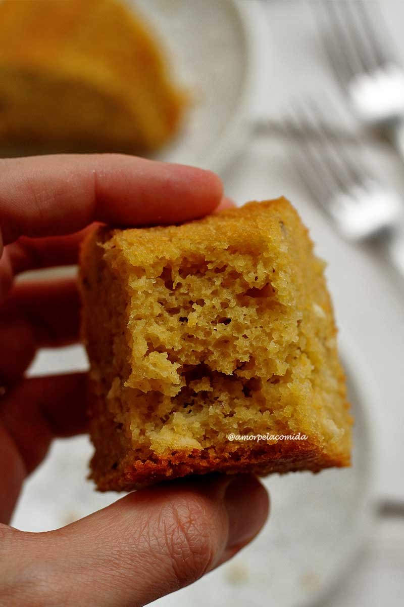 Pedaço de bolo de fubá mordido segurado na mão