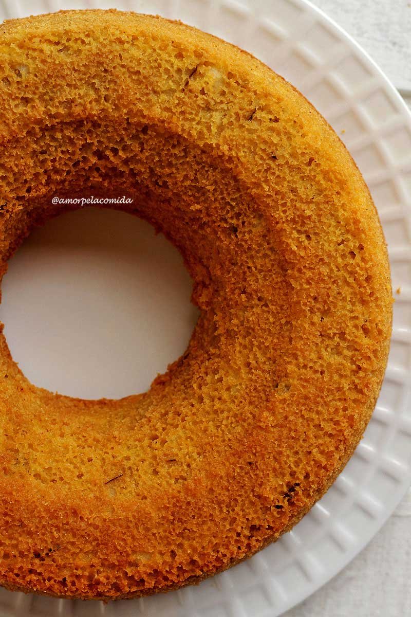 Bolo de fubá inteiro sobre prato branco visto de cima