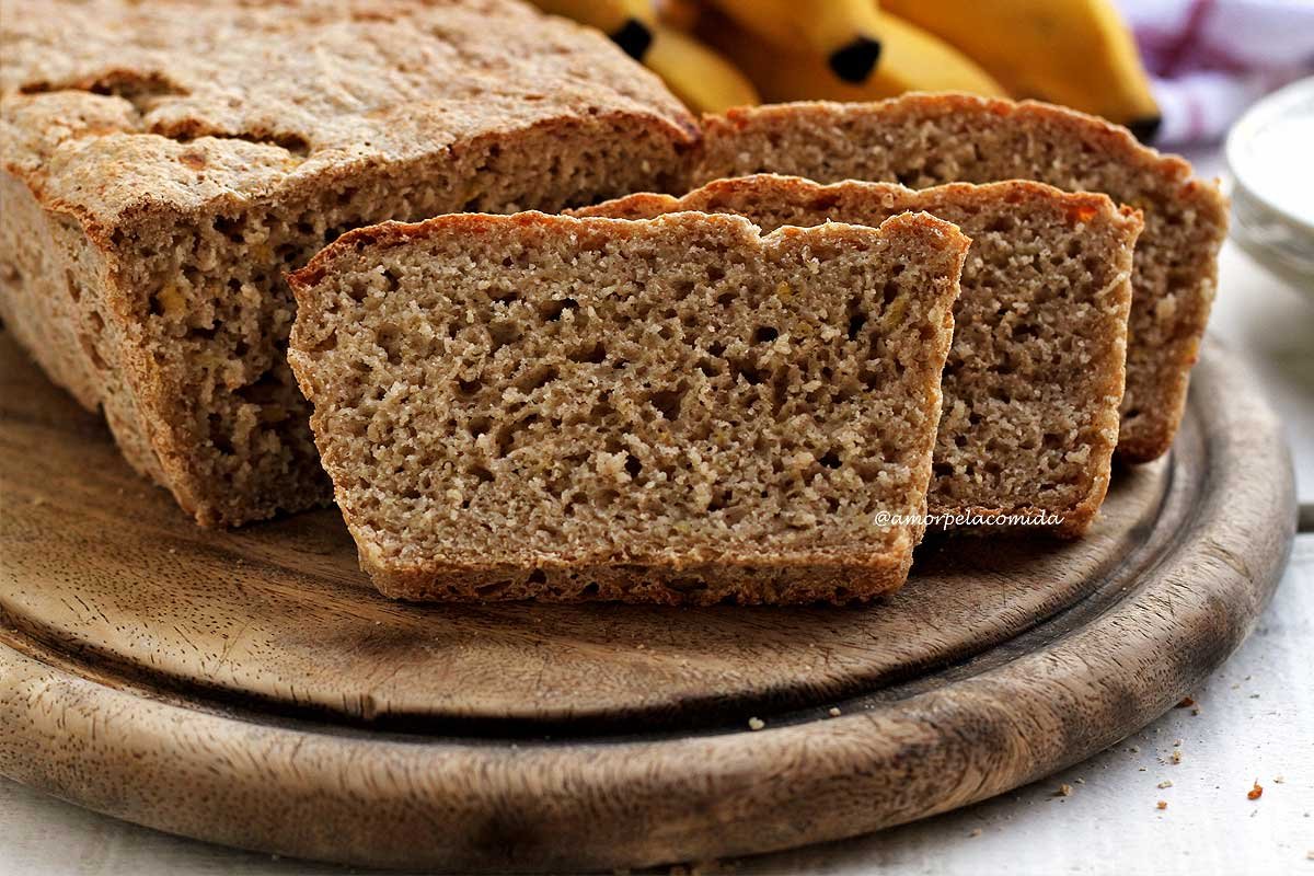 Pão de banana fatiado sobre tábua de mandeira redonda