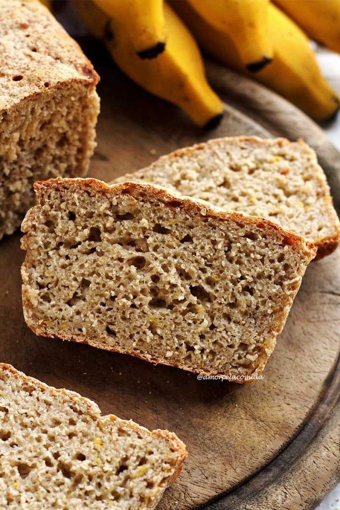 Duas fatias de pão de banana sobrepostas em uma tábua de madeira