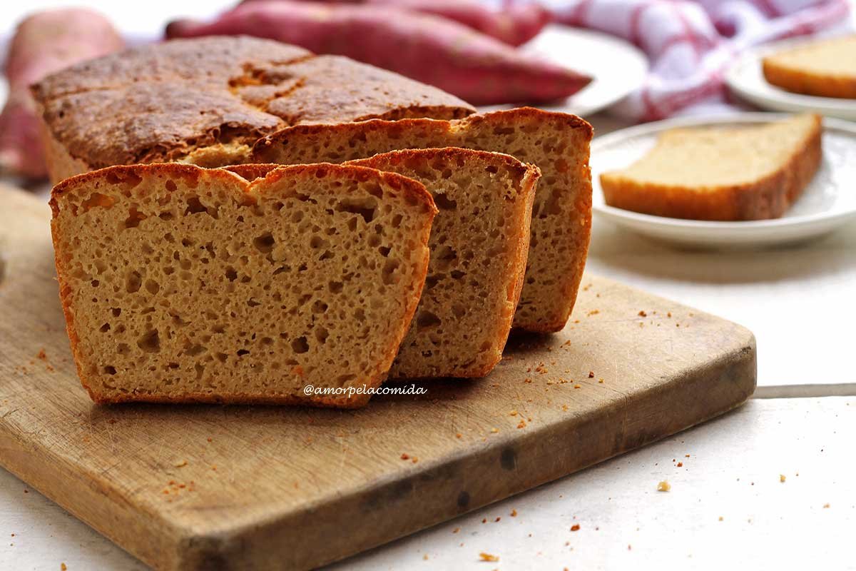 Três fatias de pão de batata doce sobre tábua de madeira em mesa branca