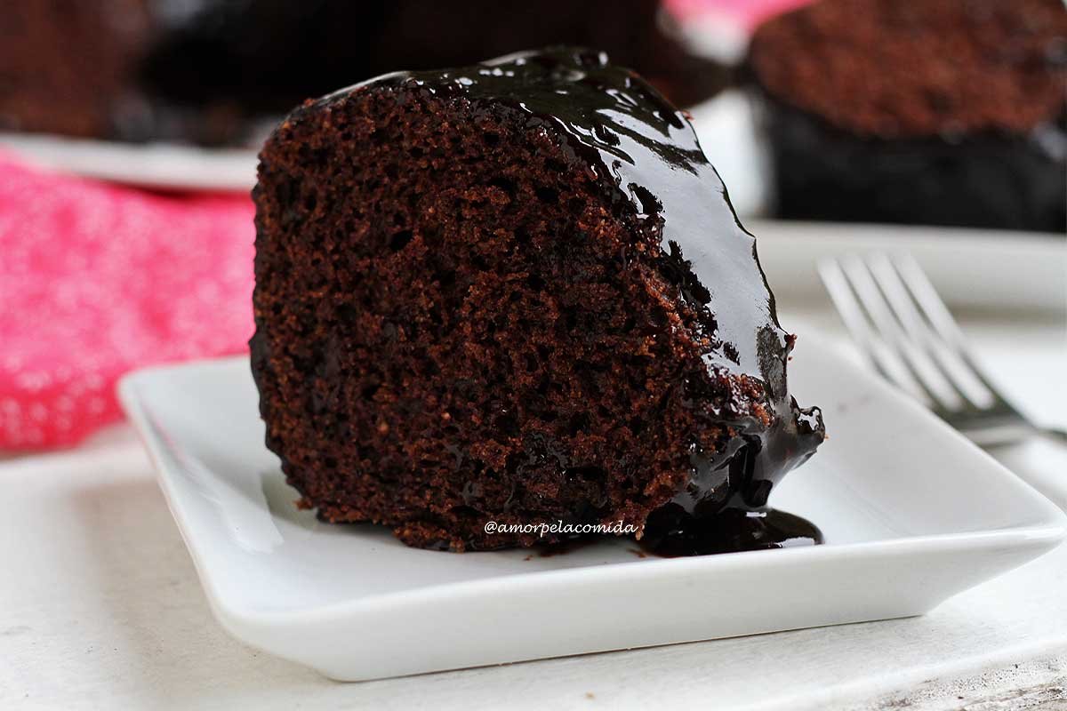 Fatia de bolo de chocolate com cobertura de chocolate sobre prato branco