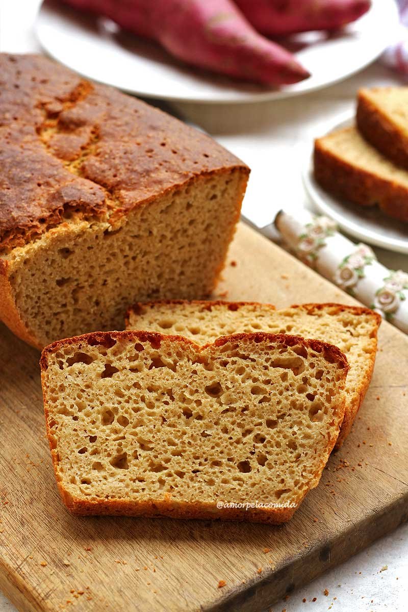 Duas fatias de pão de batata doce sobre tábua de madeira em mesa branca