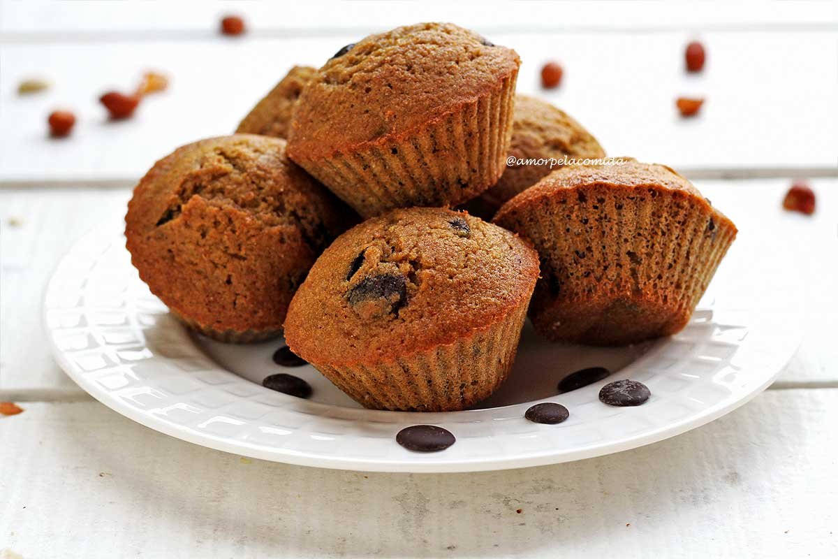 Vários bolinhos pequenos de baunilha com gotas de chocolate sobre prato branco redondo em uma mesa branca