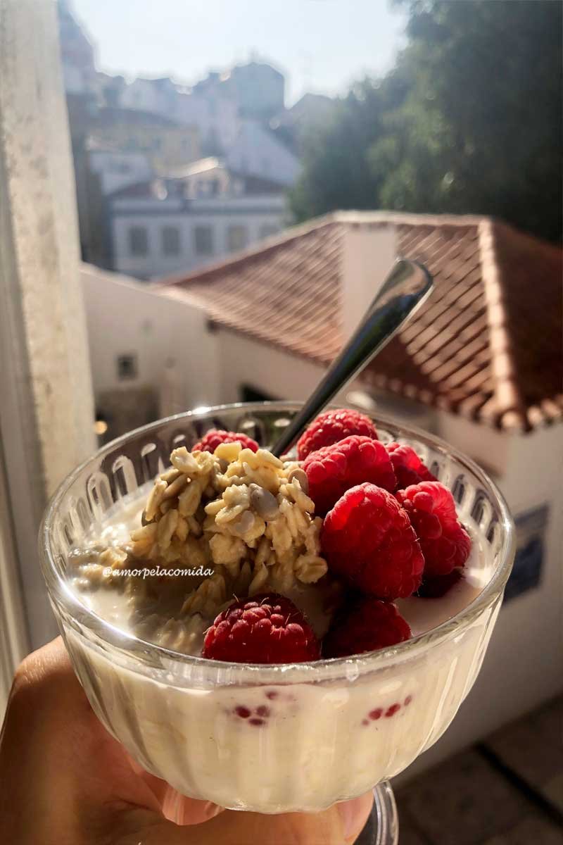 Taça de vidro com mingau de aveia e framboesas em uma janela em portugal