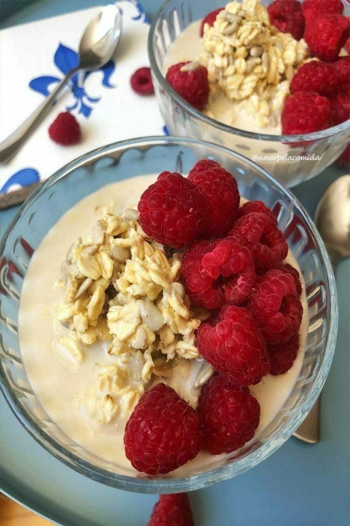 Dos platos pequeños con avena con frambuesas sobre mesa azul