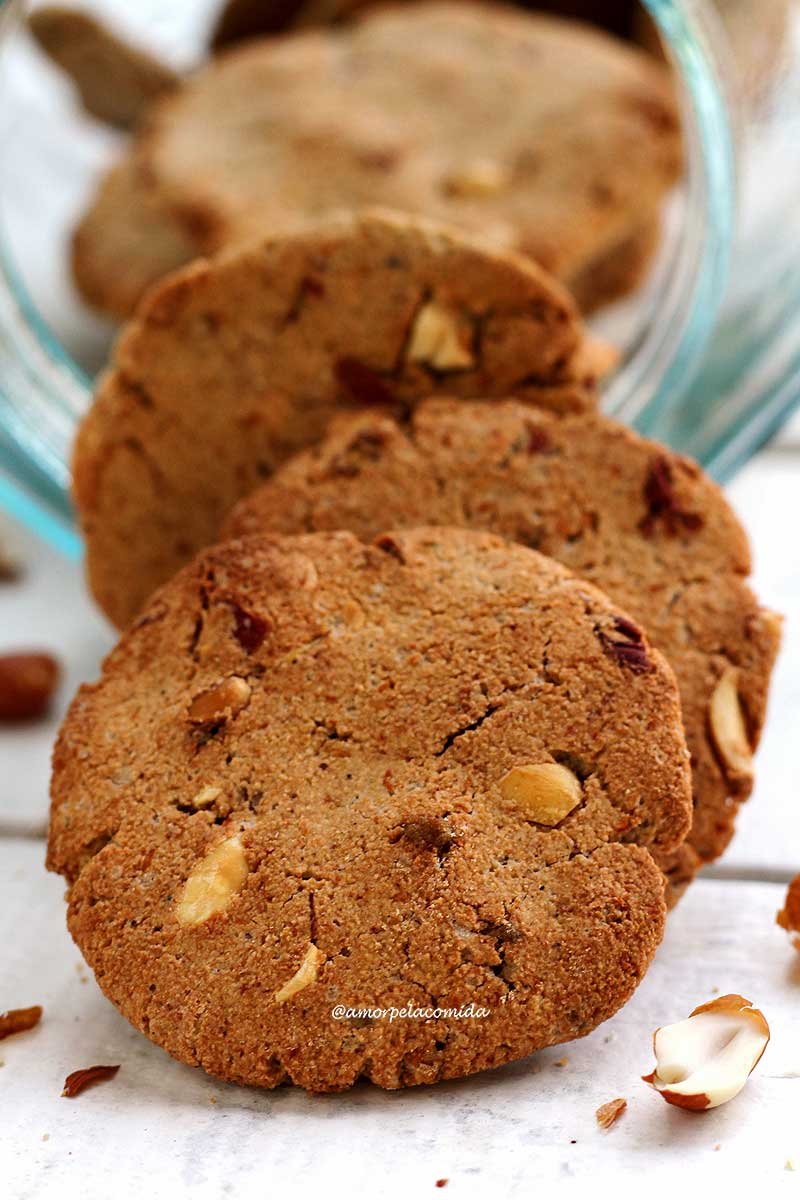 Various peanut cookies coming out of a jar on a white table