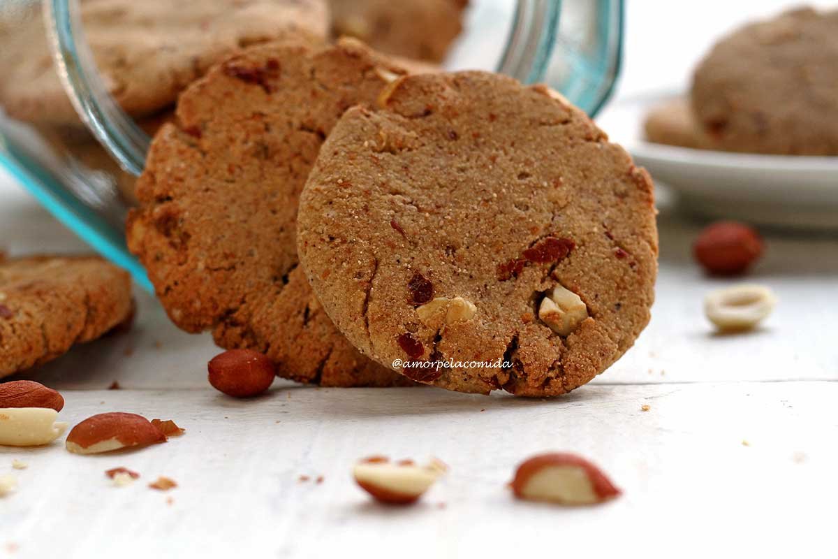 Biscoitos de amendoim encostados na borda do vidro sobre mesa branca