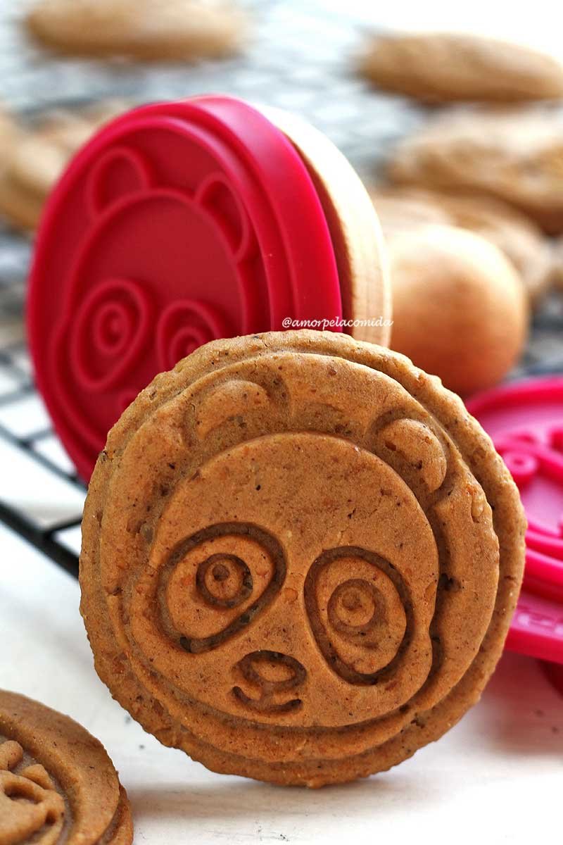 Round cookie with a panda bear face, in the background the stamp that allows the relief and a black grid with cookies