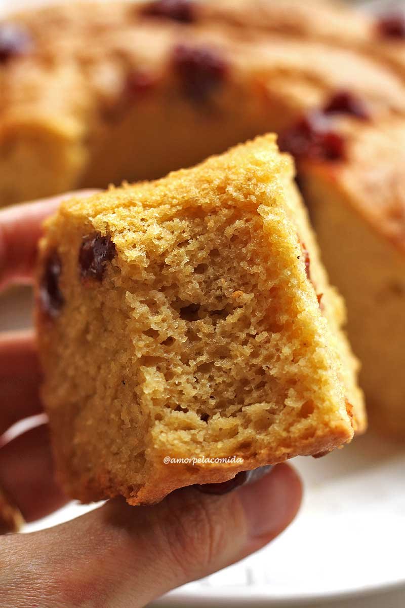 Bitten piece of cornmeal cake with guava paste being held by a hand, in the background the broken cornmeal cake is out of focus