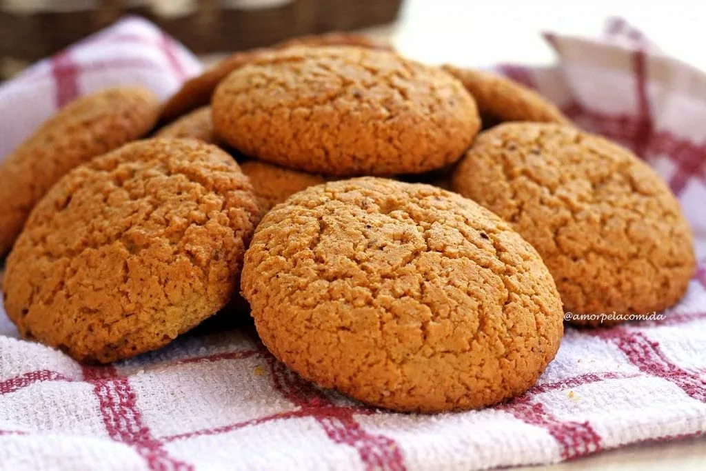 Several cornbreads piled on a round white plate, the plate is on a white dishcloth with red checks
