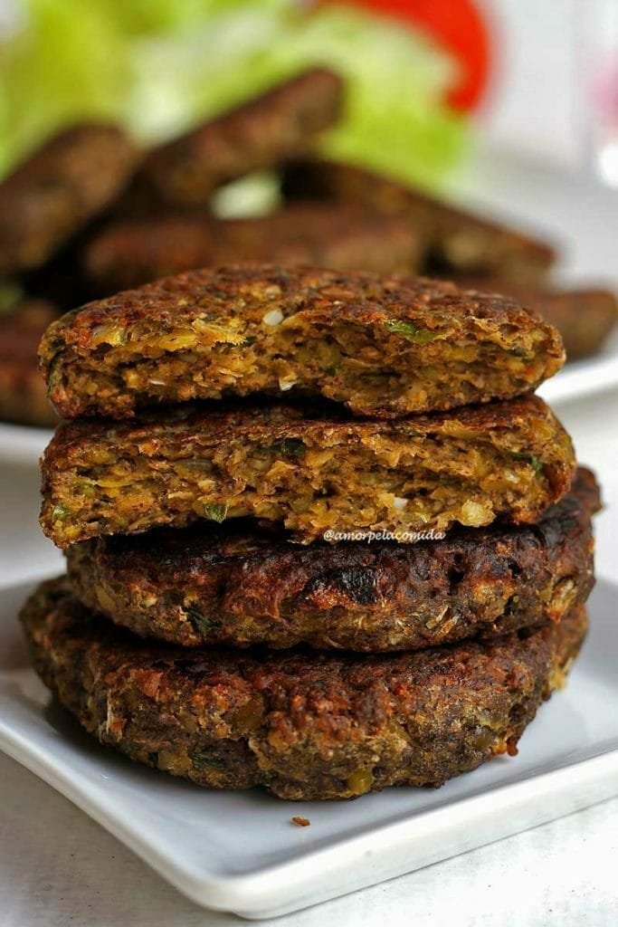 Deux hamburgers se chevauchent sur une petite assiette blanche, au-dessus des hamburgers entiers se trouvent deux moitiés d'un hamburger divisées pour montrer la texture interne