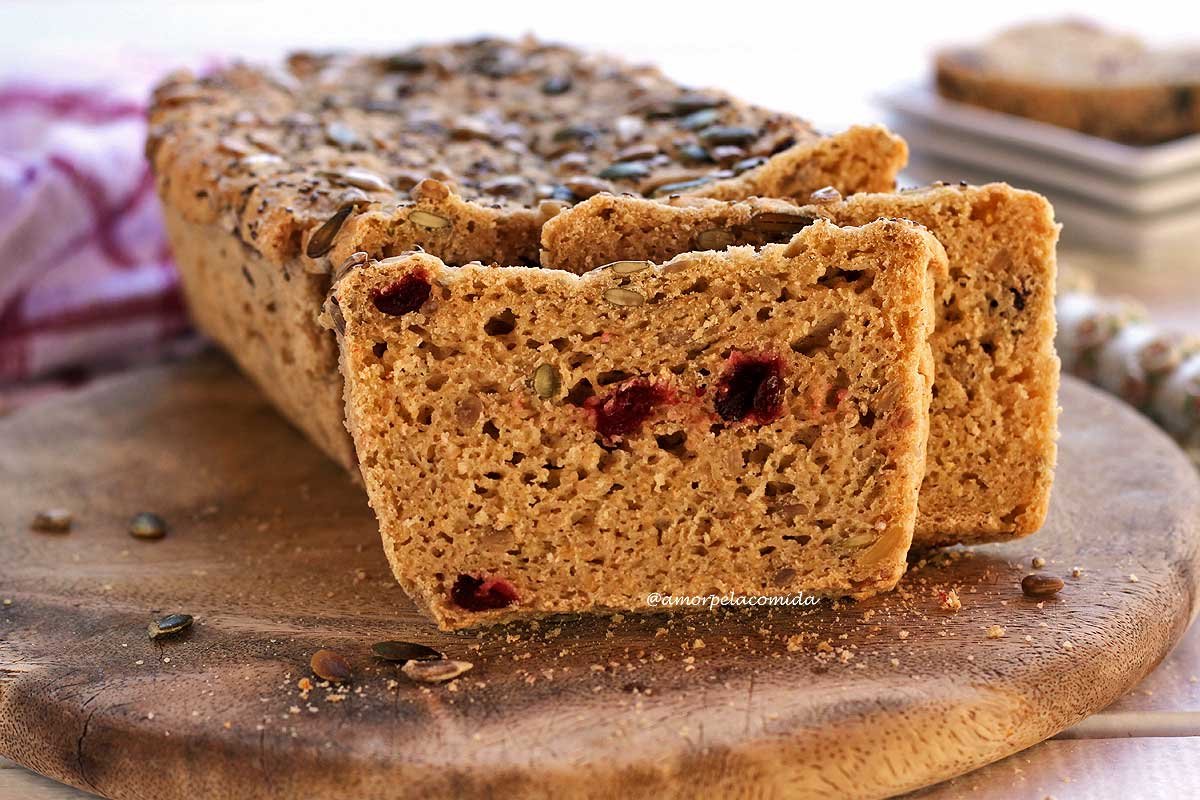 Pão de aveia com sementes e cramberries fatiado dobre uma tábua de madeira em uma mesa branca