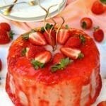 Bolo redondo de morango, no topo do bolo tem uma cobertura vermelha a base de morangos e morango cortados ao meio decorando o topo