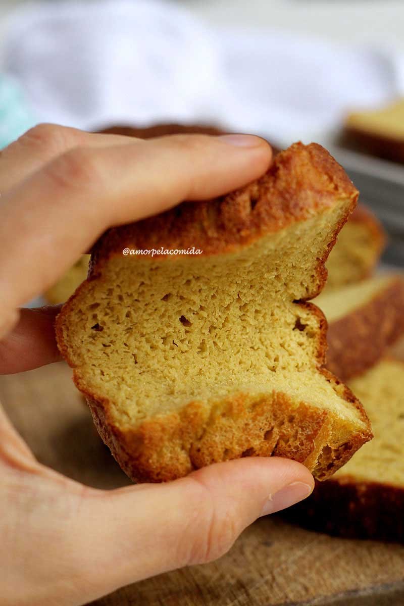 Mão segurando fatia de pão caseiro sendo pressionada pelas duas extremidades da fatia para mostrar a flexibilidade da fatia