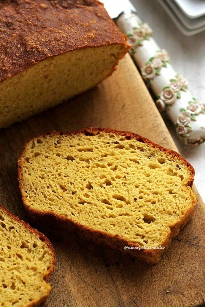 fatia de pão caseiro sobre tábua de madeira em uma mesa branca