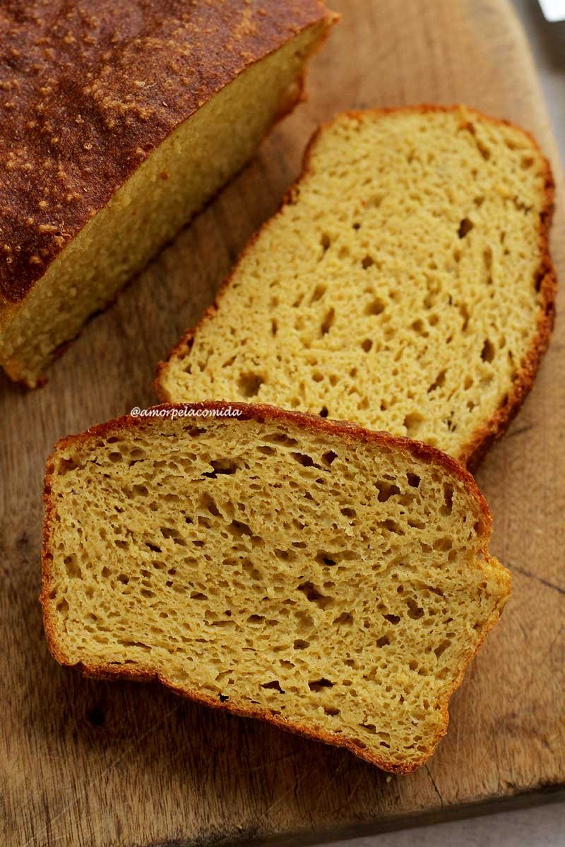 Duas fatias de pão caseiro sobrepostas em uma tábua de madeira ao lado do pão cortado