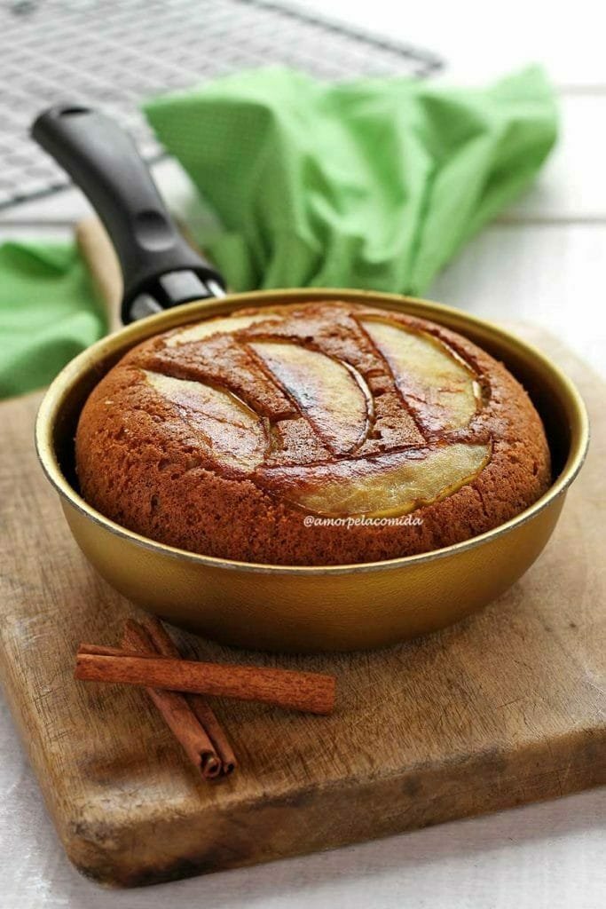 Frigideira dourada sobre tábua de madeira de cor clara em uma mesa branca