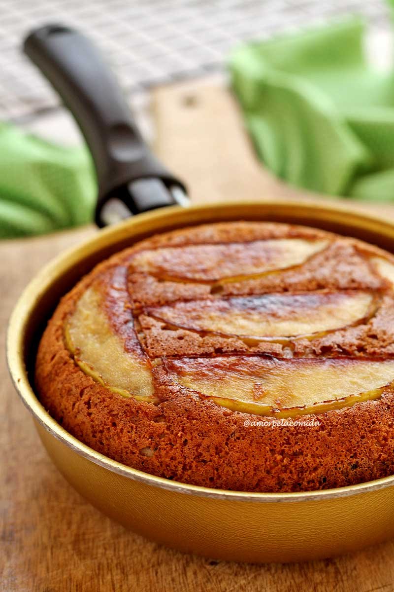 Bolo de maçã dentro de uma frigideira dourada, na parte superior do bolo fatias finas de maçã