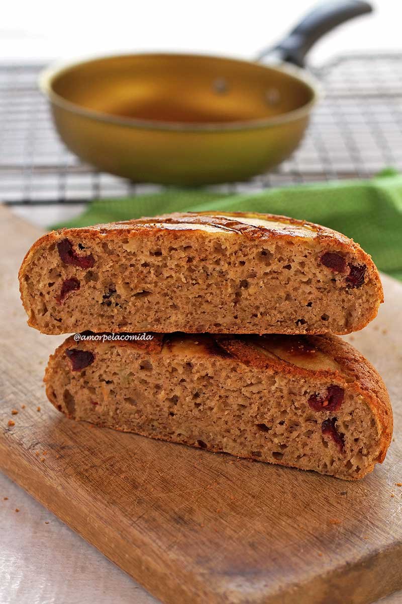 Bolo de frigideira redondo cortado ao meio, os dois pedaços estão sobrepostos sobre uma tábua de madeira de cor clara