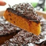 Pedaço de bolo de cenoura de frigideira sobre espátula, a frigideira com o restante do bolo está por baixo