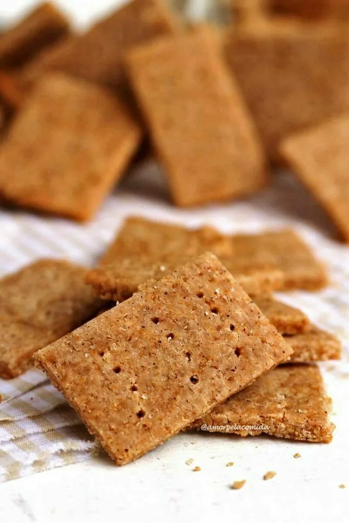 Thin, crunchy square biscuits with holes on the surface, placed on a beige and white checkered cloth