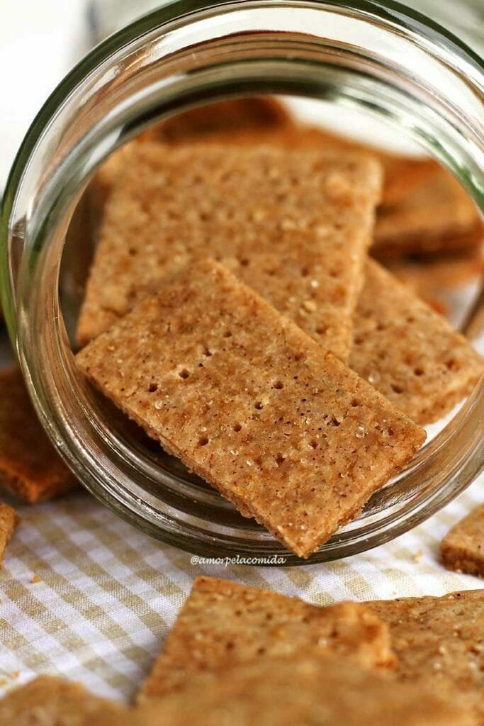 Biscoitinhos fininhos e crocantes de mel com canela saindo de dentro de um vidro transparente