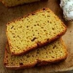 Duas fatias de pão de fubá com batata-doce sobrepostas em uma tábua de madeira
