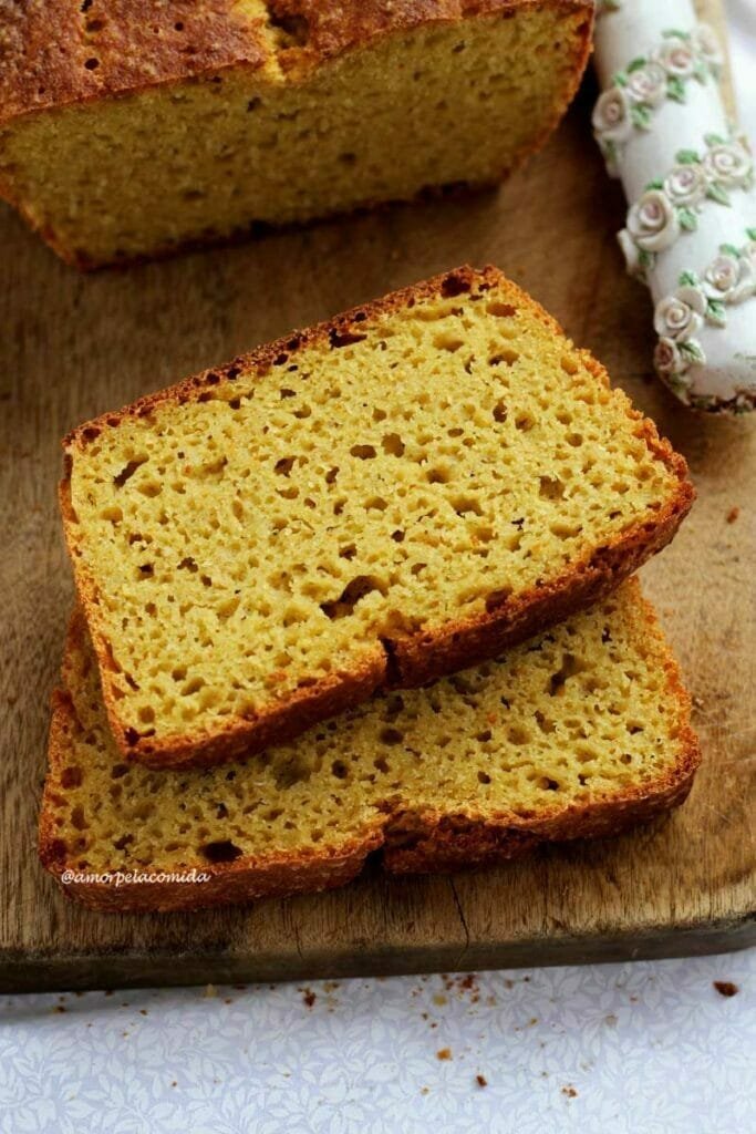 Duas fatias de pão de fubá com batata-doce sobrepostas em uma tábua de madeira