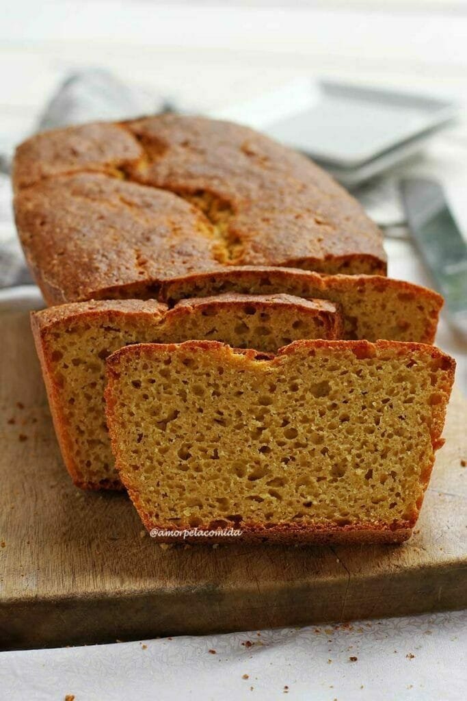 Pão de forma caseiro fatiado sobre tábua de madeira de cor clara em uma mesa branca