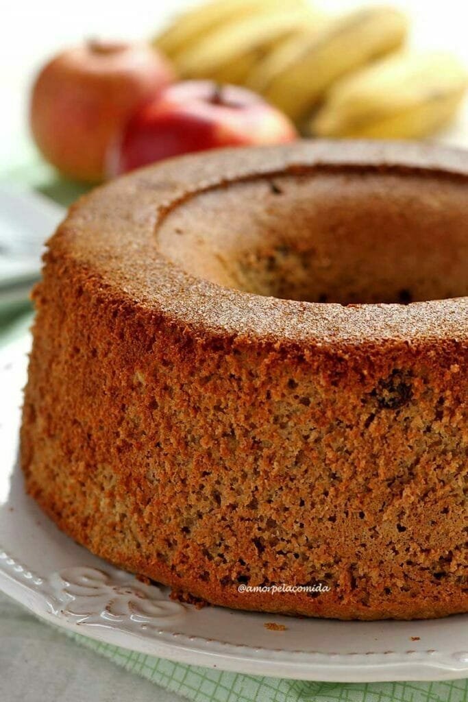 Gâteau rond avec trou au milieu sur une assiette blanche, en arrière-plan floues bananes et pommes