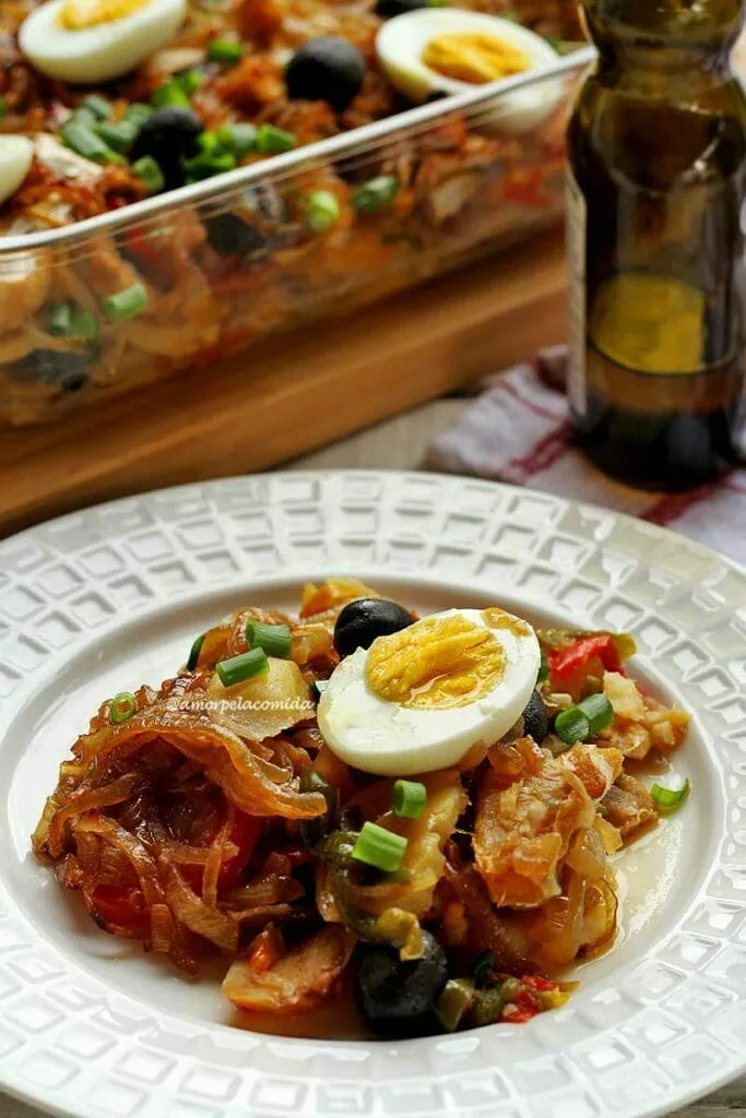 Assiette ronde blanche avec de la morue à l'intérieur, divers légumes et un demi-œuf dur sur le dessus