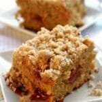 Dois pedaços de cuca com farofa sobre prato quadrado branco pequeno