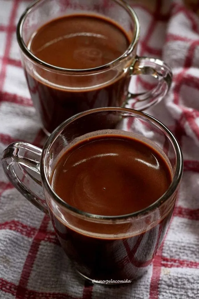 Dos tazas de chocolate caliente sobre tela a cuadros blancos y rojos
