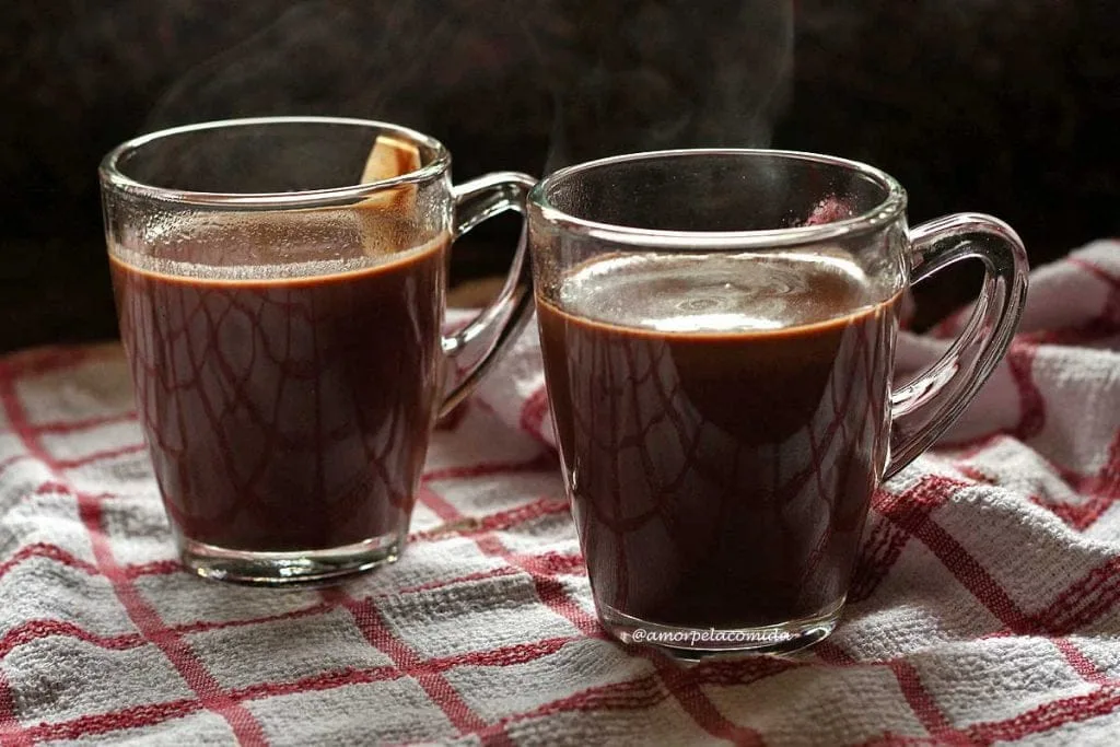 Dos tazas de chocolate caliente sobre tela blanca con cuadros rojos